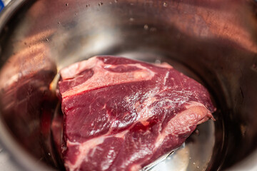 Chuck roast beef meat in kitchen saucepan pot for roasting, frying cooking and baking macro closeup cow traditional food