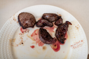 Beef spleen cow organ meat, prepared cooked food on white plate macro closeup, delicious healthy dish meal