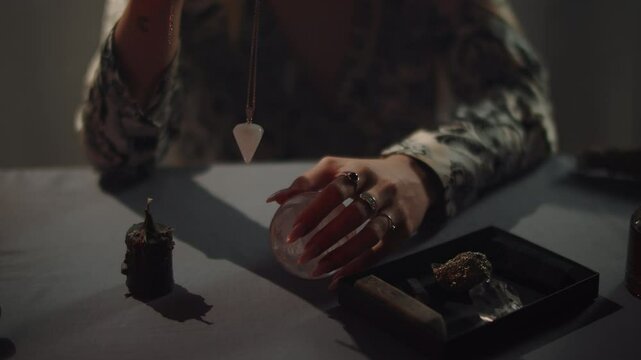 fortune teller spins pendulum in hands, magic rituals