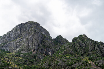 Kotor Skurda canyon, Montenegro cliff mountains near old fort fortress trail hike in rain clouds, nature landscape view by water bay in summer