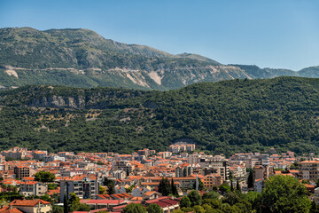 Budva Montenegro cityscape skyline view on canyon mountains, high angle aerial landscape by roof rooftops of residential buildings in summer
