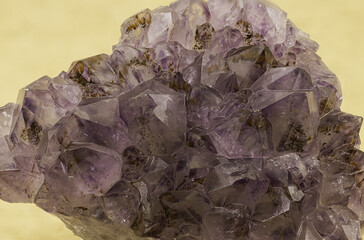 Exquisite amethyst crystal cluster showcased against a yellow backdrop, capturing the gem's rich purple hues and natural geometric facets