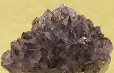 Exquisite amethyst crystal cluster showcased against a yellow backdrop, capturing the gem's rich purple hues and natural geometric facets