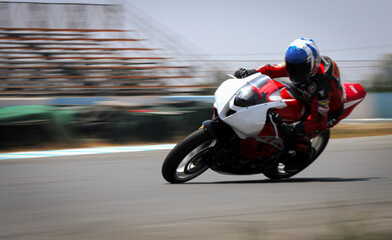 Obraz premium Motorcycle racer speeding and leaning into curve on racetrack