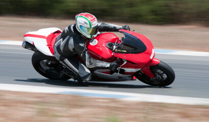 Motorcycle racer speeding and leaning into curve on racetrack