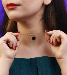 Minimalist gold choker necklace with black charm held by model, macro shot of handmade accessory,...