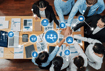 A top-down view of a collaborative business meeting showcasing teamwork and technology with diverse professionals discussing data analysis and strategies in a modern office setting. Amity