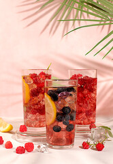 Modern still life with berry juice, raspberries, blueberries, red currants and oranges on elegant kitchen table with long hard shadows. Minimal detox diet concept, summer vitamin drinks.