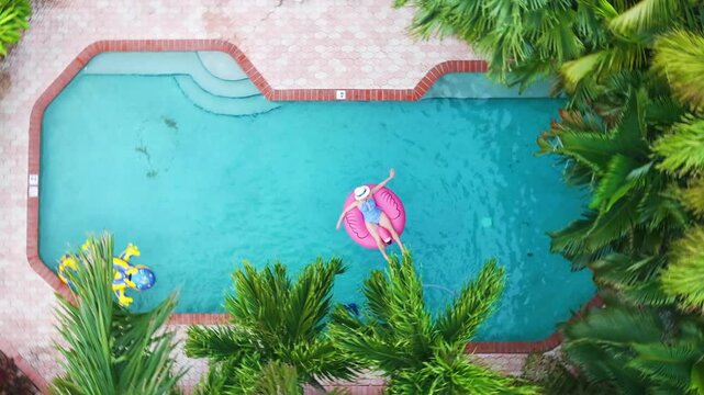 This stunning aerial view highlights a serene Florida pool area with a whimsical flamingo float, lush greenery, and colorful patio furniture, creating an ideal oasis for relaxation
