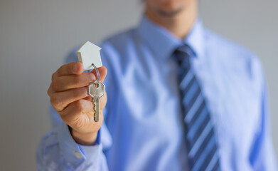 A professional in a light blue shirt and striped tie holds a keyring with two keys and a...