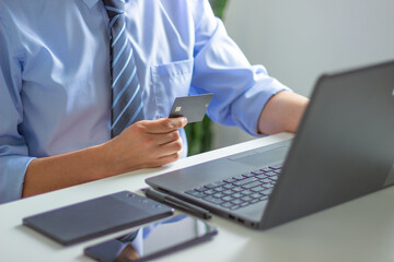 A professional in a rolled-sleeve light blue button-up holds a smartphone with both hands and sports a black smartwatch. Blurred background emphasizes digital focus.