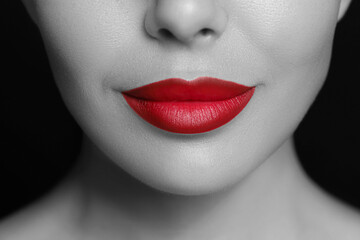 Fototapeta premium Young woman with beautiful red lips, closeup. Black and white effect with color accent