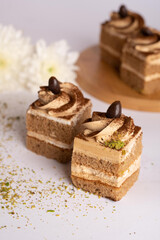 Coffee cream layer cake cube topped with chocolate swirl and coffee bean decoration, served on white background, macro photo in soft light, ideal for bakery branding, dessert menu, catering visuals