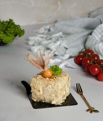 Elegant layered salad covered in crispy potato chips and topped with physalis fruit and parsley,...