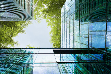 Modern buildings and lush trees against blue sky, double exposure. View from below