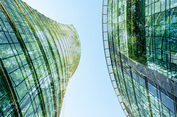Modern buildings and lush trees against blue sky, double exposure. View from below
