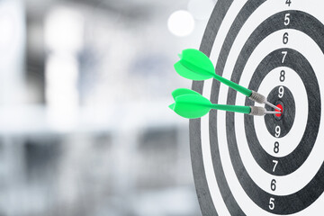 Targeting and business success. Darts sticking in center of dartboard in office, closeup