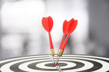 Targeting and business success. Darts sticking in center of dartboard in office, closeup
