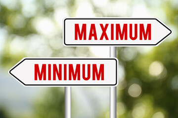 Signposts with Maximum and Minimum arrows pointing in different directions against blurred green...