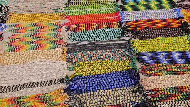 A vibrant display of handcrafted beaded jewelry, including bracelets, necklaces, and colorful decorative pieces, meticulously arranged at a local artisan market in Chapala.