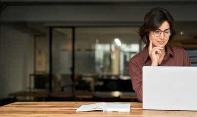 Busy young business woman executive using laptop in office. Hispanic businesswoman company worker...