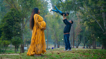 Young pregnant woman with her husband and child, enjoying outdoor, indian family concept
