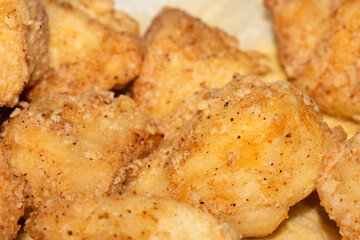 Close up of crispy frying chicken being fried in a batter in a pan