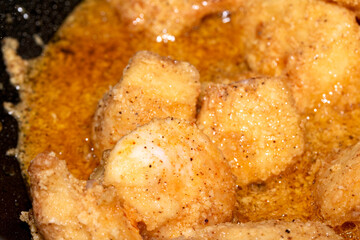 Close up of crispy frying chicken being fried in a batter in a pan