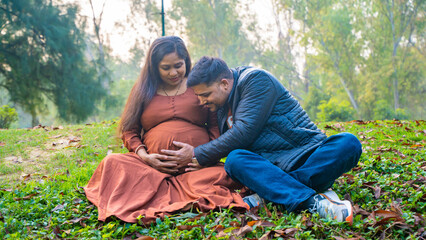 Fototapeta premium Happy pregnant couple in outdoor park, Husband with his pregnant wife in nature, married indian couple expecting baby concept