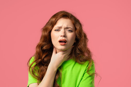 Pretty woman has sore. Sick lady with swollen throat on pink studio. Angina. Young girl feels pain, ache. Seasonal flu, cold disease.