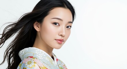 A serene young woman with long, flowing hair wears a floral-patterned kimono. Her elegant beauty stands out against a soft background, perfect for showcasing cultural themes.
