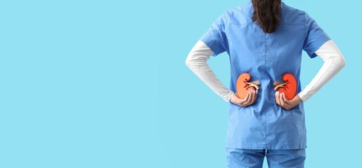 Female doctor holding paper kidneys on light blue background with space for text, back view