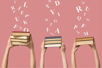 Hands holding many books on pink background