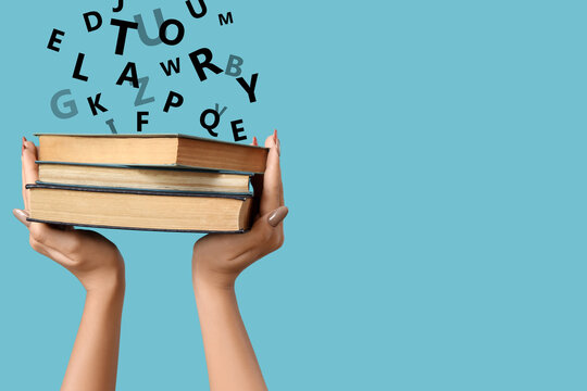 Hands holding books on blue  background