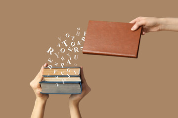 Hands holding many books on beige background