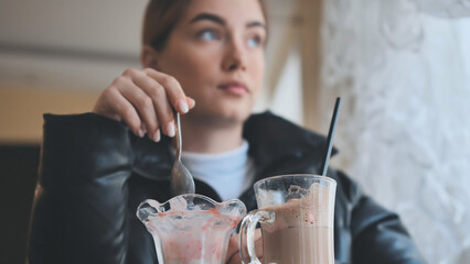 Woman relaxing at cafe, sipping milkshake, enjoying ice cream during quiet afternoon break