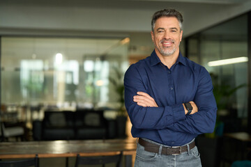 Happy confident professional businessman of middle age, mature business owner, company manager ceo executive at work. Smiling mature business man leader standing arms crossed in office. Portrait.
