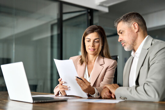 Business woman lawyer manager holding legal documents consulting mature older client at office meeting, two professional executives experts discussing financial accounting papers working together.