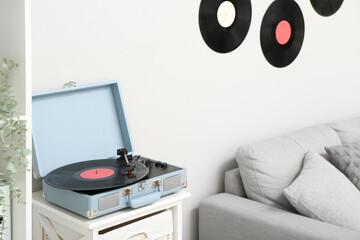 Record player with vinyl disk on shelf in living room