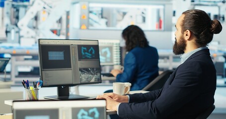 Photovoltaics factory worker using PC to monitor performance of robot arms placing solar panels on assembly lines. Expert at computer desk looking on screen, inspecting solar plant machinery, camera B