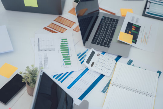 Overwhelmed Workspace with Laptop and Financial Reports