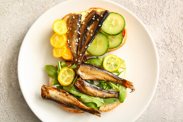 Plate of tasty sandwiches with canned smoked sprats on grey background