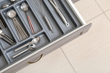 Open kitchen drawer with different silver cutlery