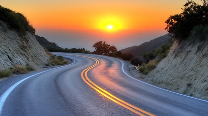 A winding mountain road leads toward the vibrant setting sun