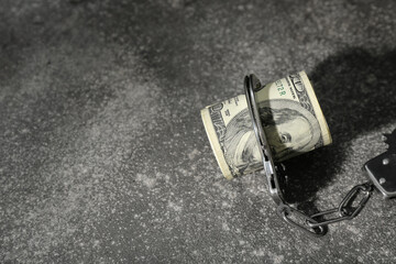 Handcuffs with dollar banknotes on dark background. Sanctions concept