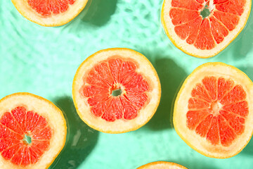 Slices of fresh grapefruit in water on turquoise background