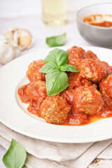 Plate of tasty meat balls with sauce on light background