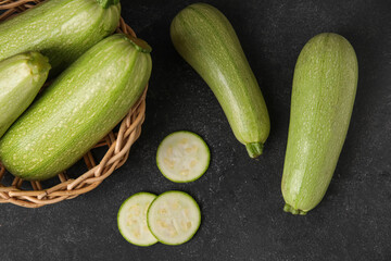 Wicker basket with fresh zucchini on black background