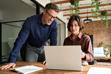 Busy business man and woman leaders colleagues talking working on computer at workplace. Two happy professional executives company team people working in corporate office using pc laptop computer.