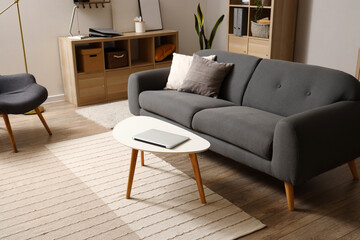 Interior of modern living room with sofa and laptop on table